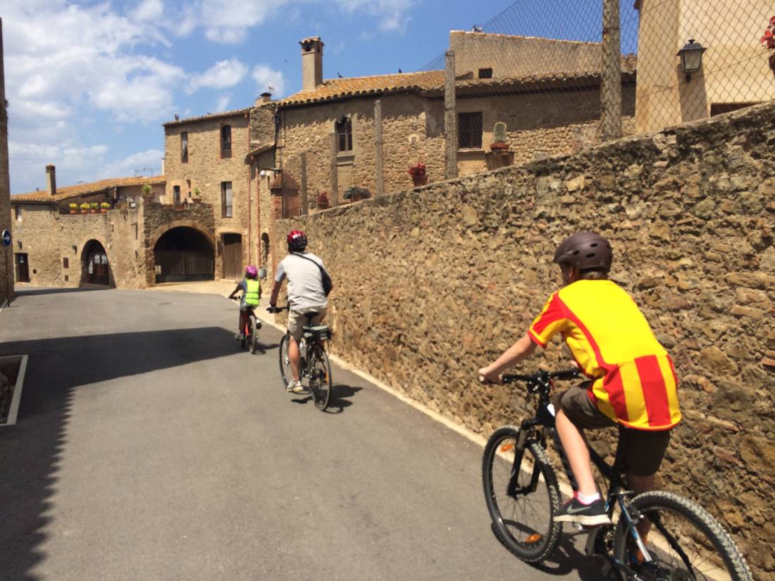 Family cycling through a village in Catalonia on a self guided cycle trip |  <i>Kate Baker</i>