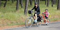 Parent riding with child on a trail-a-bike in Provence, France