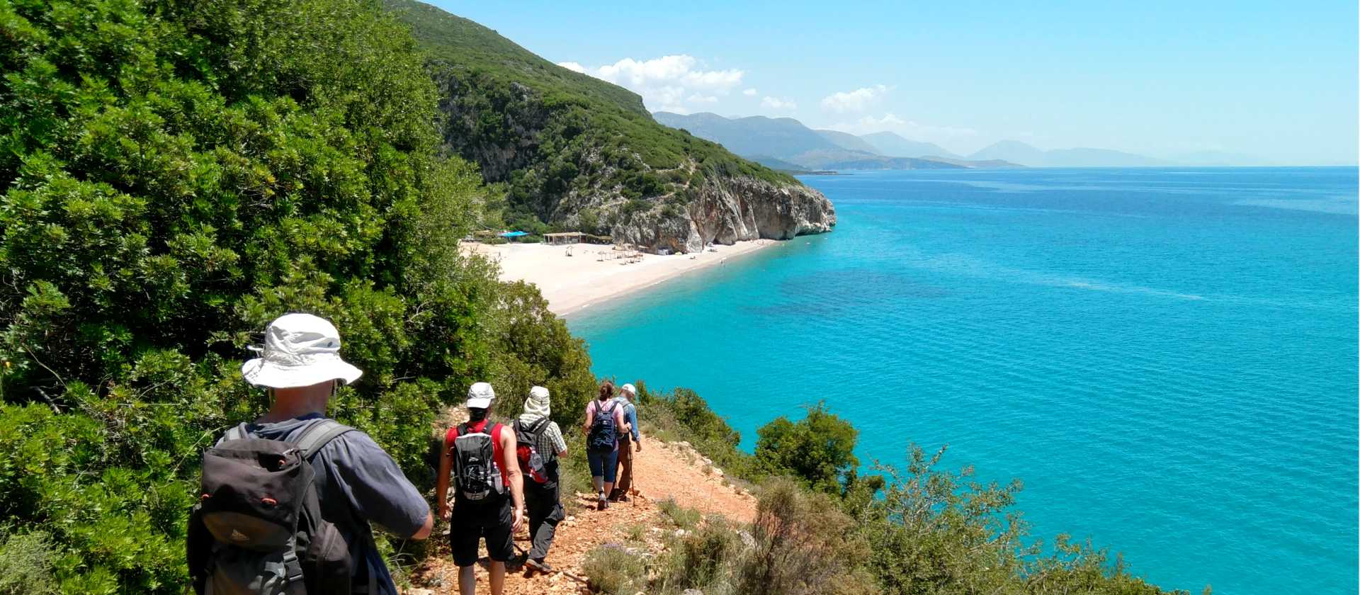 Hikers descending a coastal trail to a beautiful beach in Albania