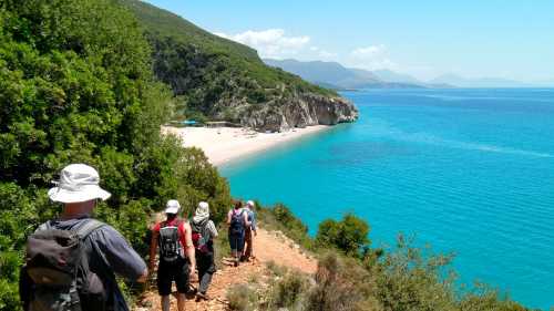 Hikers descending a coastal trail to a beautiful beach in Albania