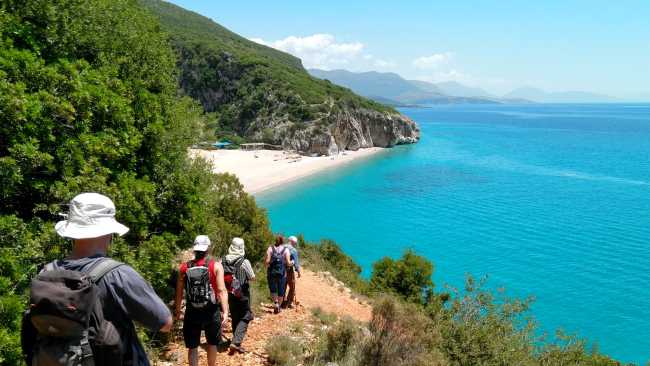 Hikers descending a coastal trail to a beautiful beach in Albania