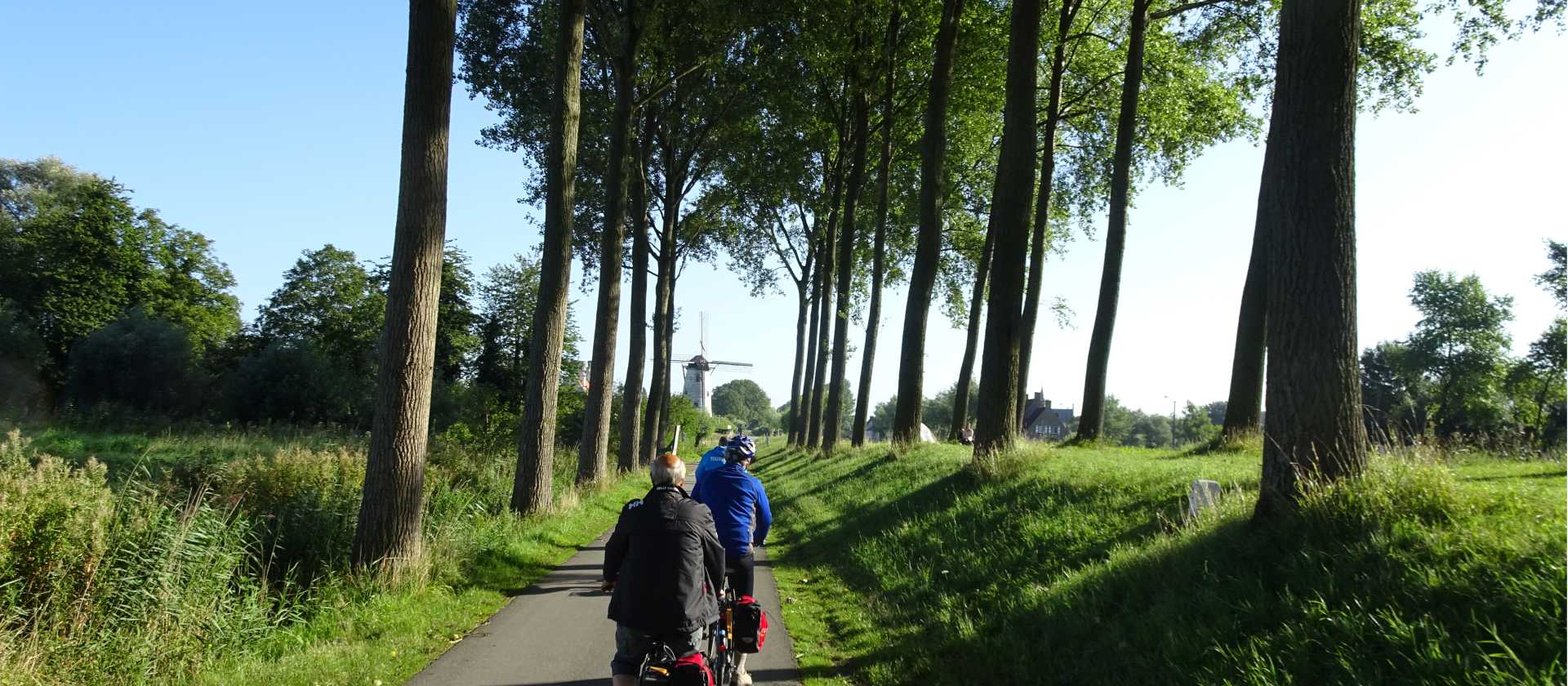Bike and barge cyclists approaching a windmill in Belgium