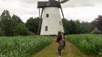 Friends cycling past one of Belgium's stunning windmills.