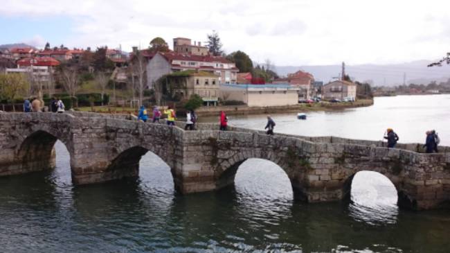 Pilgrims crossing a bridge along the Portuguese Way