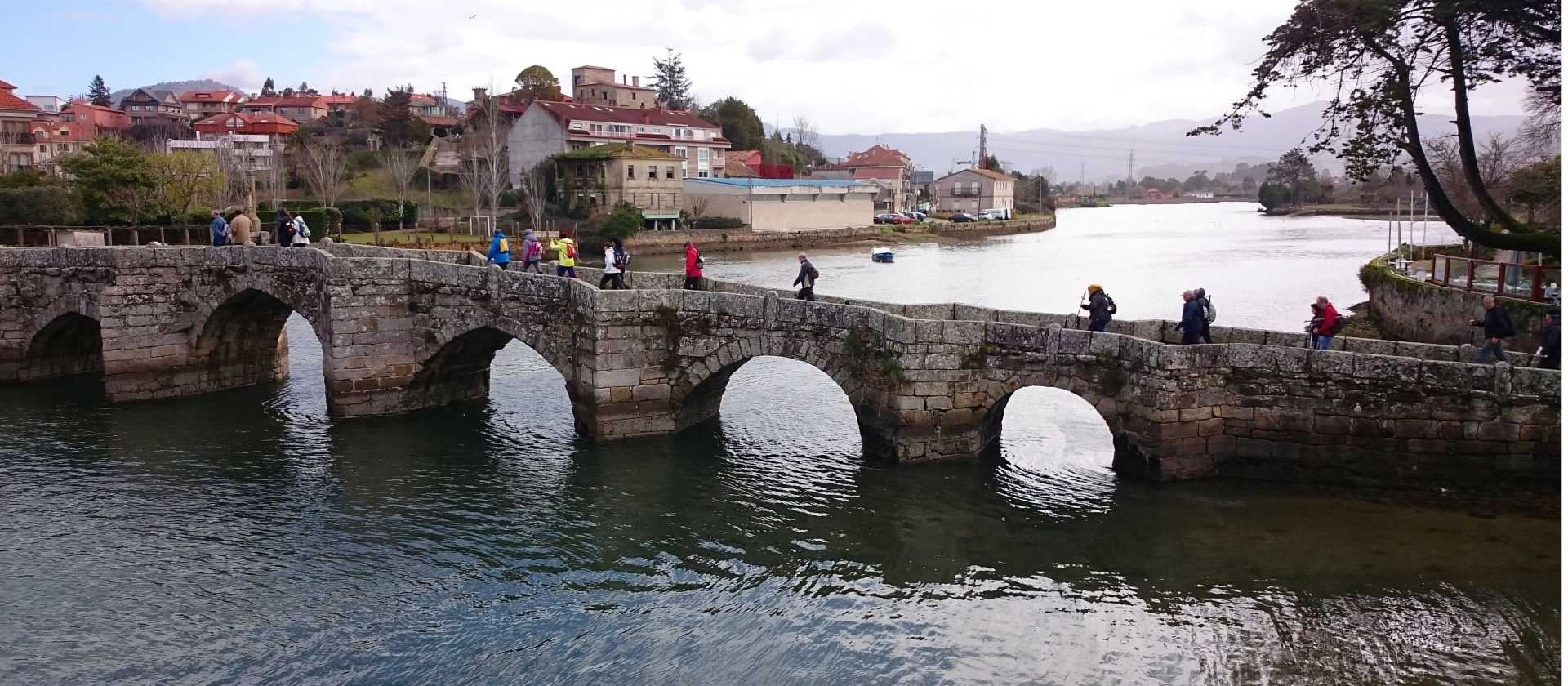 Pilgrims crossing a bridge along the Portuguese Way