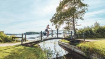 Woman cycling on a scenic wooden bridge in Denmark.