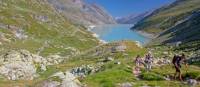 Group ascending a mountain on the Tour de Monte Rosa Walk above a stunning alpine lake | Andrew Bain