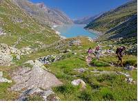 Group ascending a mountain on the Tour de Monte Rosa Walk above a stunning alpine lake |  <i>Andrew Bain</i>