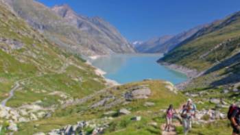 Group ascending a mountain on the Tour de Monte Rosa Walk above a stunning alpine lake