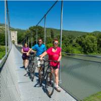 Cyclists crossing the Passerelle Himalayenne, the suspension bridge at Rochemaure enroute to Orange