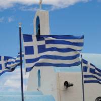 Greek flags flying above a white washed church in the Peloponnese