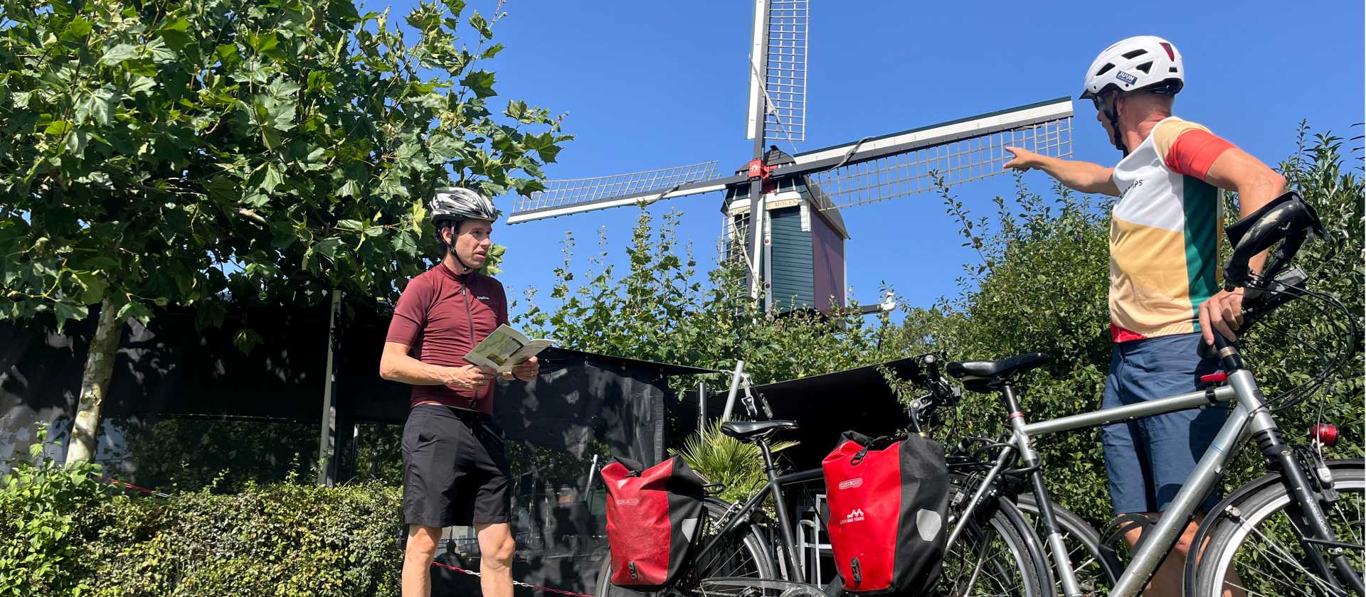 Cycling the Pieterpad Trail, two riders pause beside a windmill in the Netherlands.