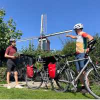 Cycling the Pieterpad Trail, two riders pause beside a windmill in the Netherlands.