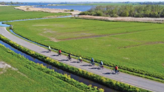Cyclists enjoying the flat polder landscape of northern Holland