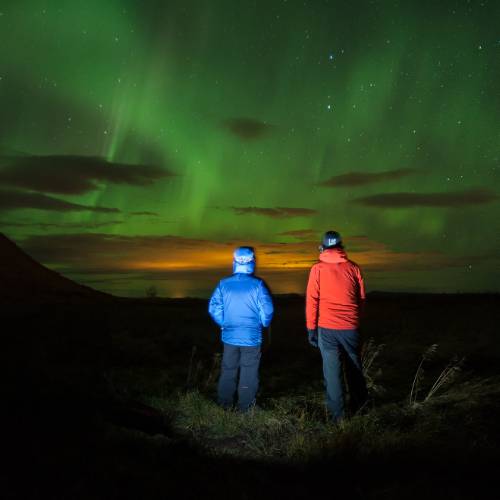 Travellers watching the breathtaking Northern Lights in a remote part of Iceland