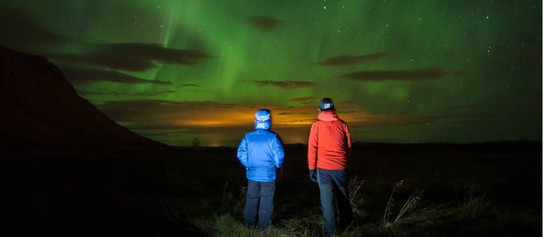 Travellers watching the breathtaking Northern Lights in a remote part of Iceland