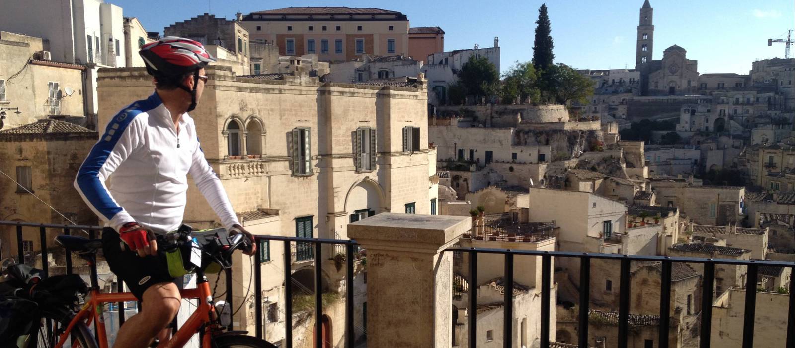 Cyclist viewing the historic cave dwellings in the Sassi di Matera | Kate Baker