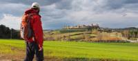 A walker admiring the hilltop town of Monteriggioni on the Via Francigena, Italy | Brad Atwal