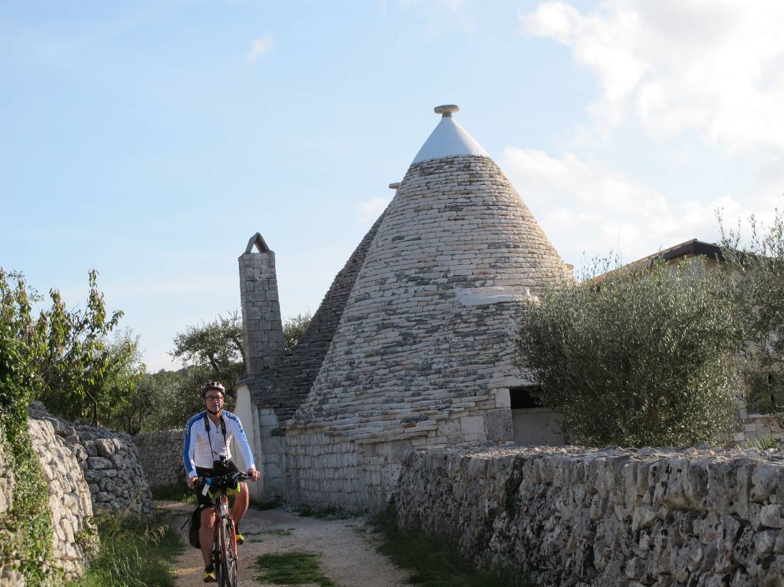 Cyclist passing a trulli house in Puglia |  <i>Kate Baker</i>