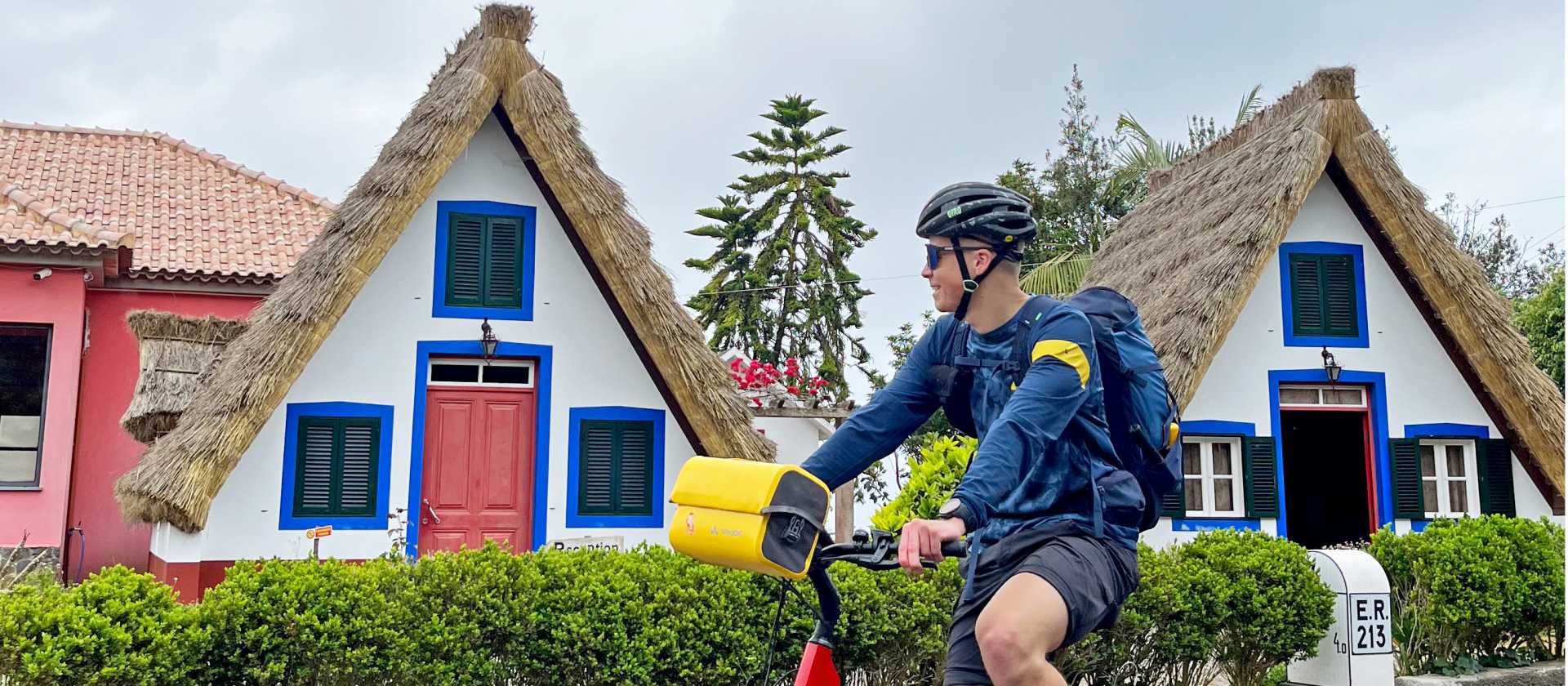 Cyclist passing traditional houses in Santana