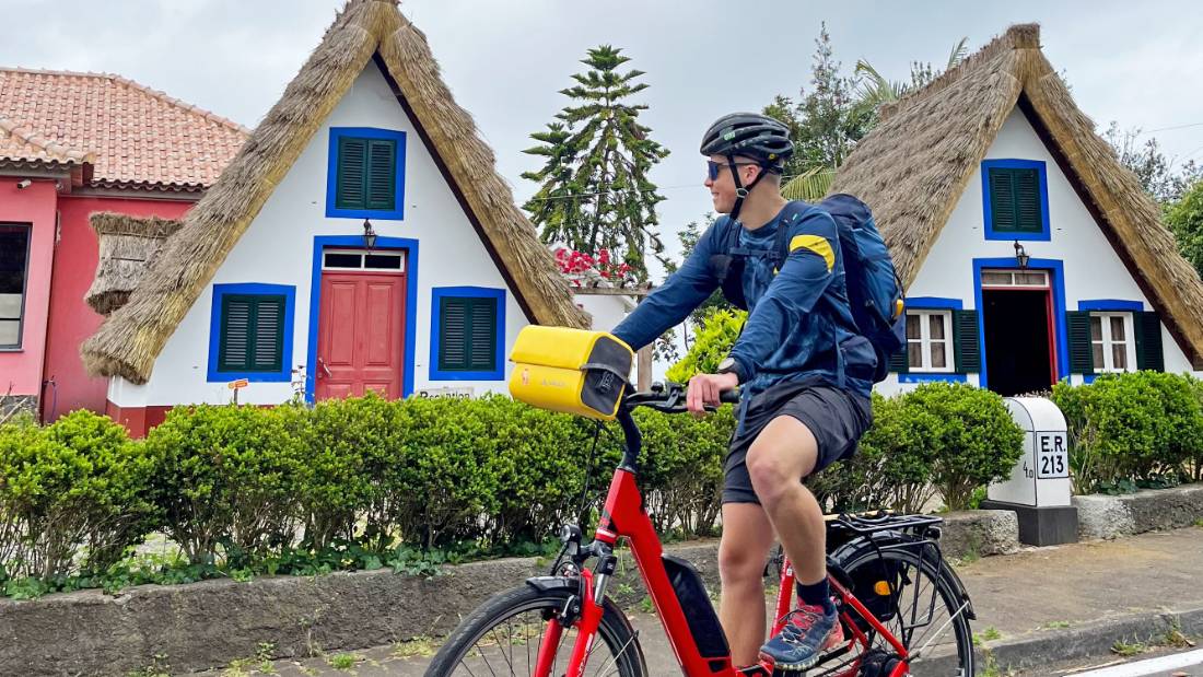 Cyclist passing traditional houses in Santana