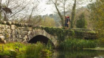 A pilgrim crosses an ancient bridge over the Neiva River in Portugal