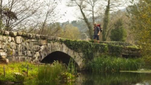 A pilgrim crosses an ancient bridge over the Neiva River in Portugal | Miguel Da Santa