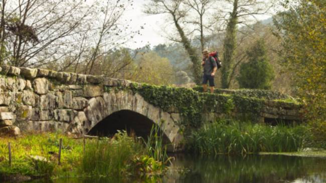 A pilgrim crosses an ancient bridge over the Neiva River in Portugal | Miguel Da Santa
