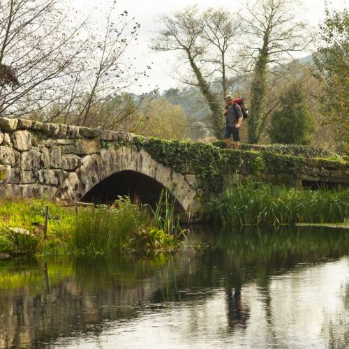 A pilgrim crosses an ancient bridge over the Neiva River in Portugal