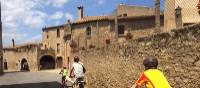 Family cycling through a village in Catalonia on a self guided cycle trip | Kate Baker