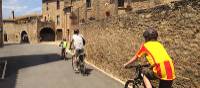 Family cycling through a village in Catalonia on a self guided cycle trip | Kate Baker