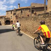 Family cycling through a village in Catalonia on a self guided cycle trip | Kate Baker