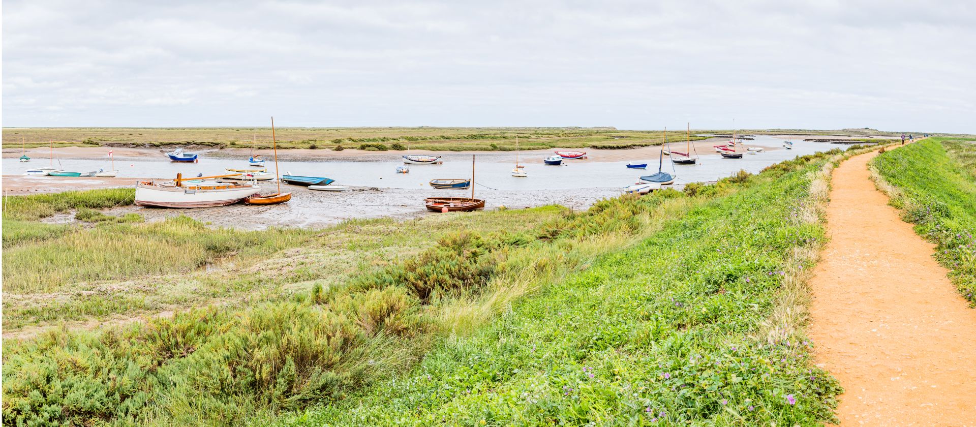 Norfolk Coast Path leads past moored boats on the salt marsh