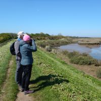 Norfolk Coast Path walkers pause to view a tidal estuary with binoculars | Peter Wells