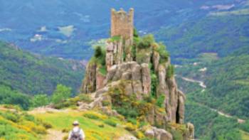 A walker follows the path to Chateau de Rochebonne